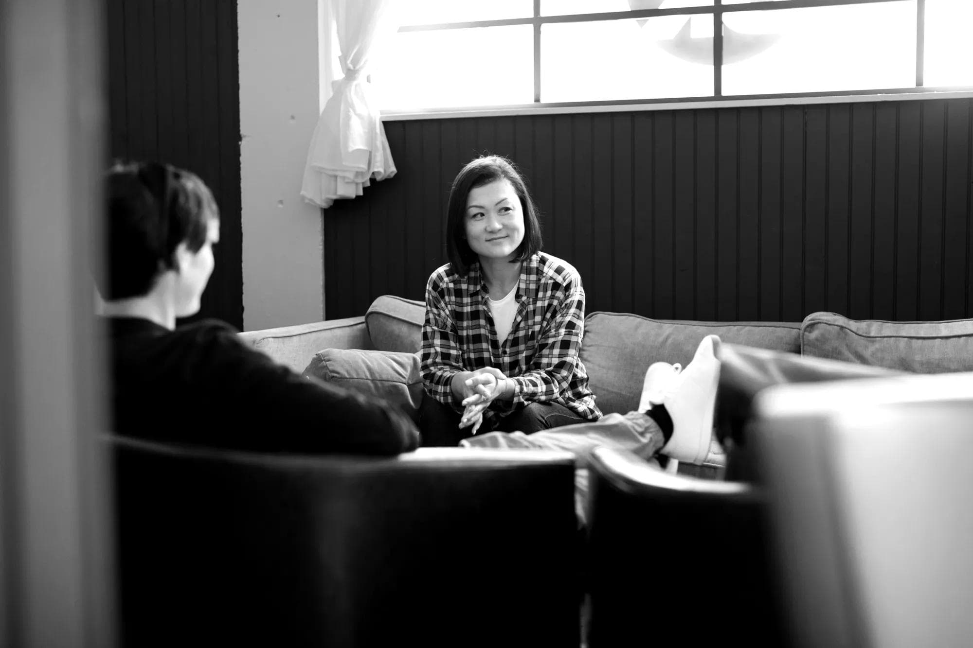 A woman sitting on a couch next to a window thinking about how to hire tech talent.